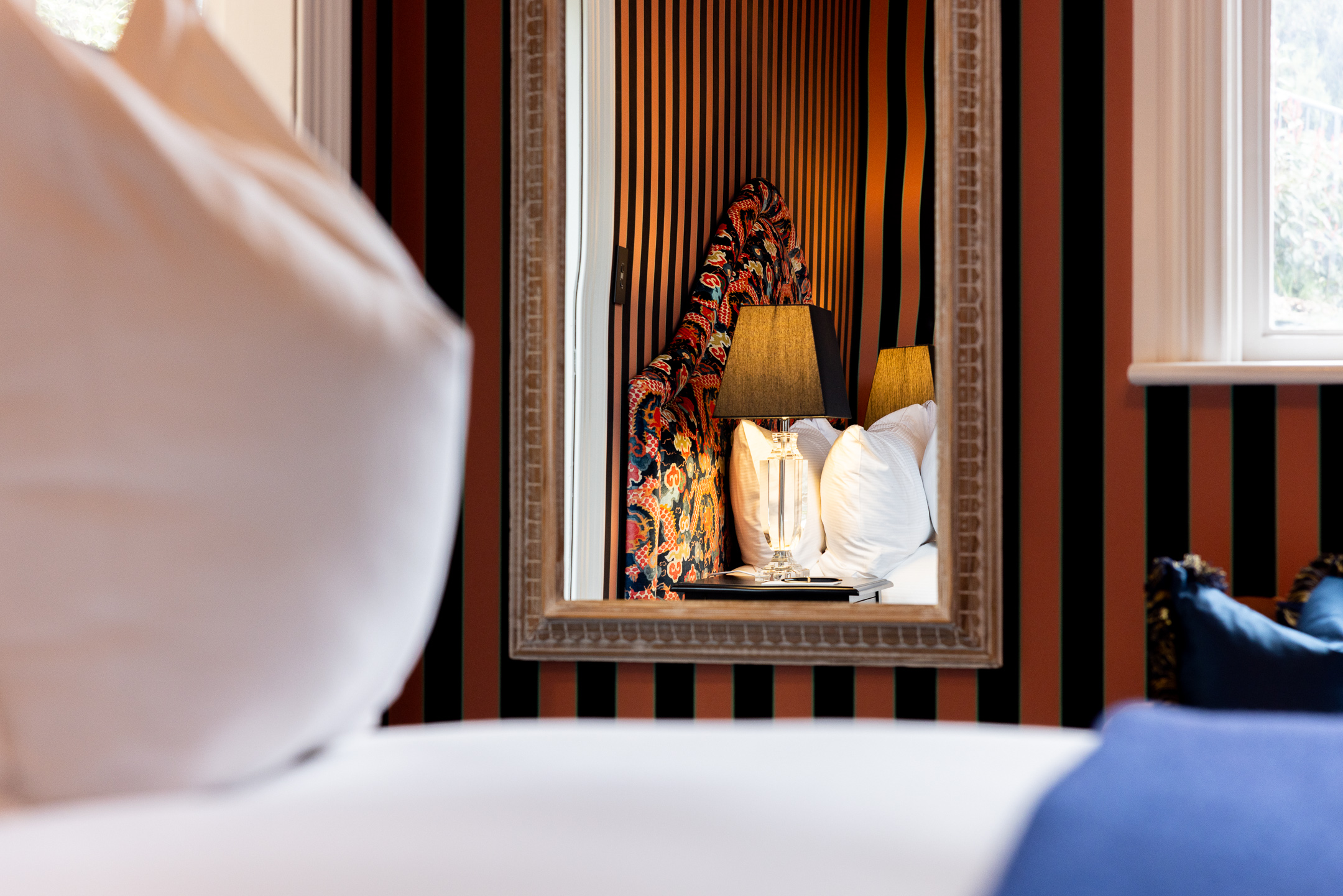 The bedroom of the McFarlane Room at Hulbert House reflected in the antique full length mirror
