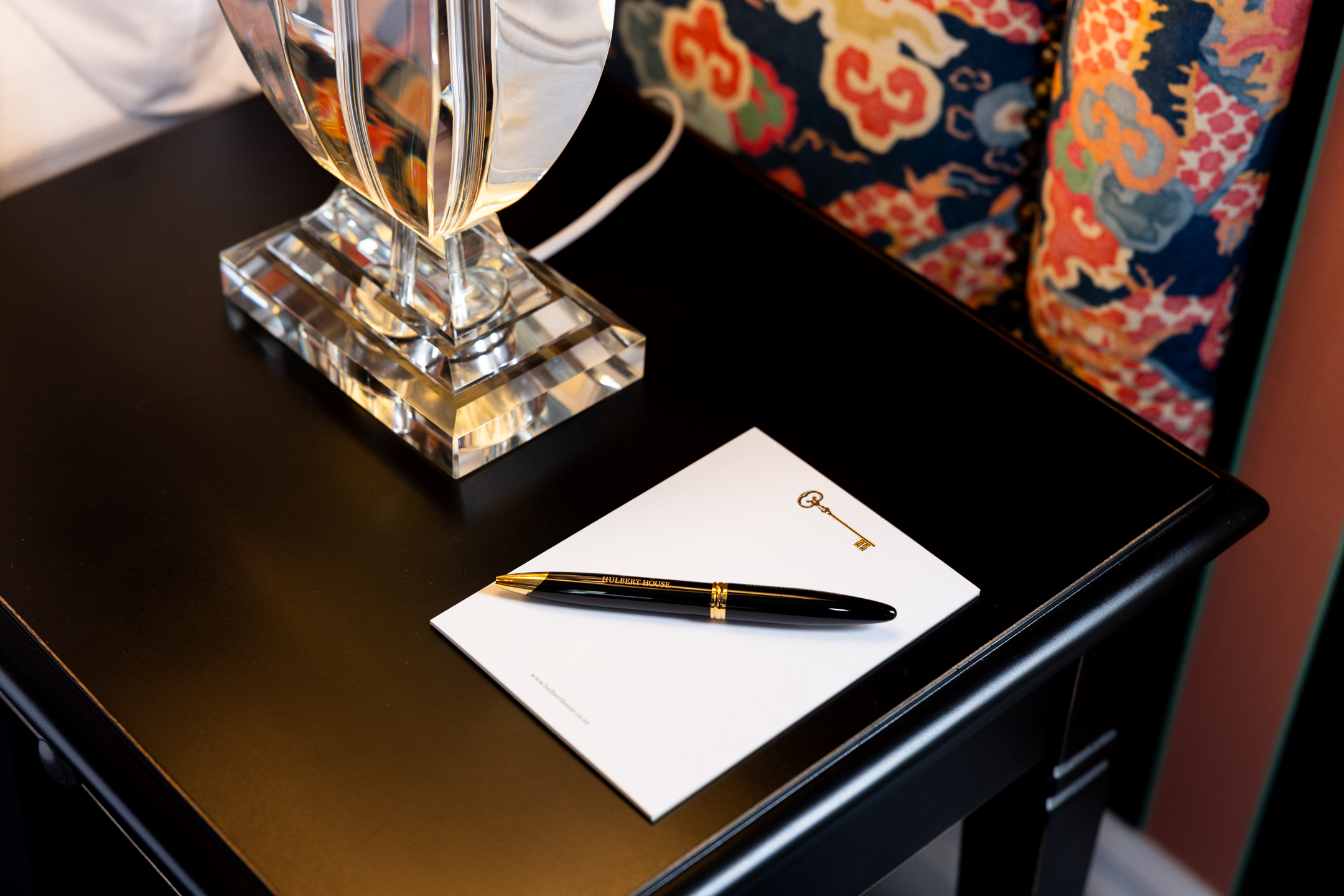 n image of the bedside table with Hulbert House branded note pad and pen in the McFarlane Room